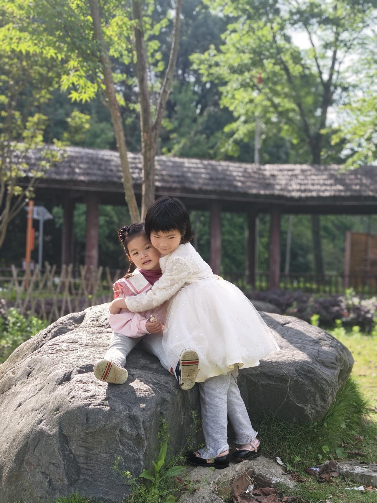 五月阳光明媚，两个小女孩在一起玩耍，天真烂漫，无忧无虑。