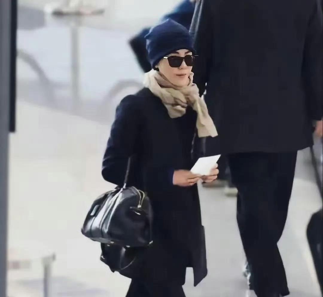 55岁穿一身黑走机场。
没有logo，没有助理打伞。
网友分两派吵翻了。
一派说
