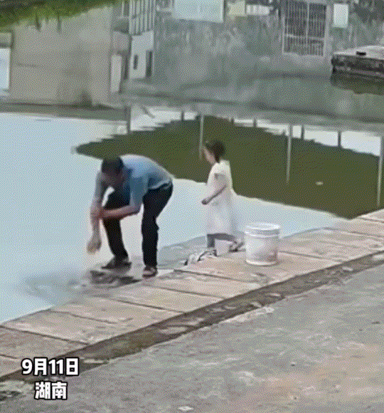 湖南，一爷爷在无护栏的池塘边洗手，不料随行的年幼孙女见状后，也模仿爷爷的动作凑到