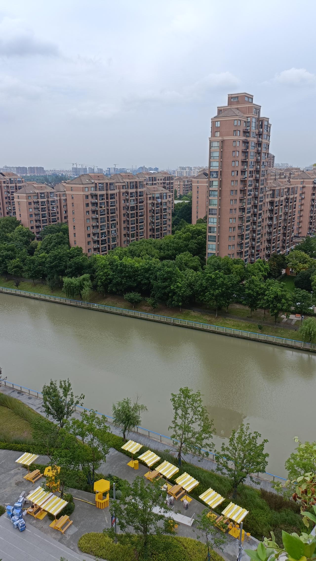 河畔的宁静时光，绿树掩映下的现代住宅区。
上联：河畔楼阁映碧波，
下联：人间烟火