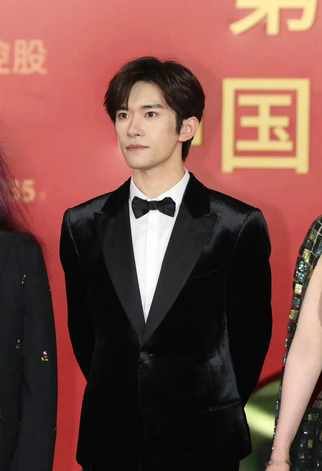 当天易烊千玺以黑西装搭粉衬衫的造型亮相红毯，他一出现现场就爆发出热烈的尖叫声和欢