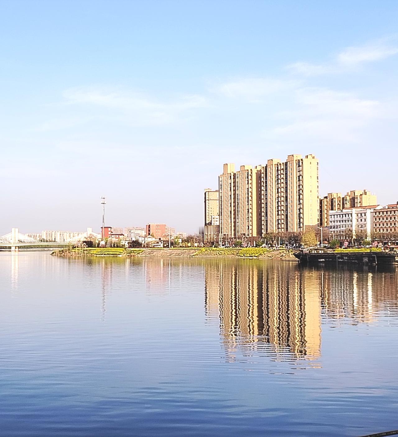 蓝天白云，高楼大厦在水中倒影，看到这美景，我站在沈丘槐店十八孔大闸上，随手拍下天