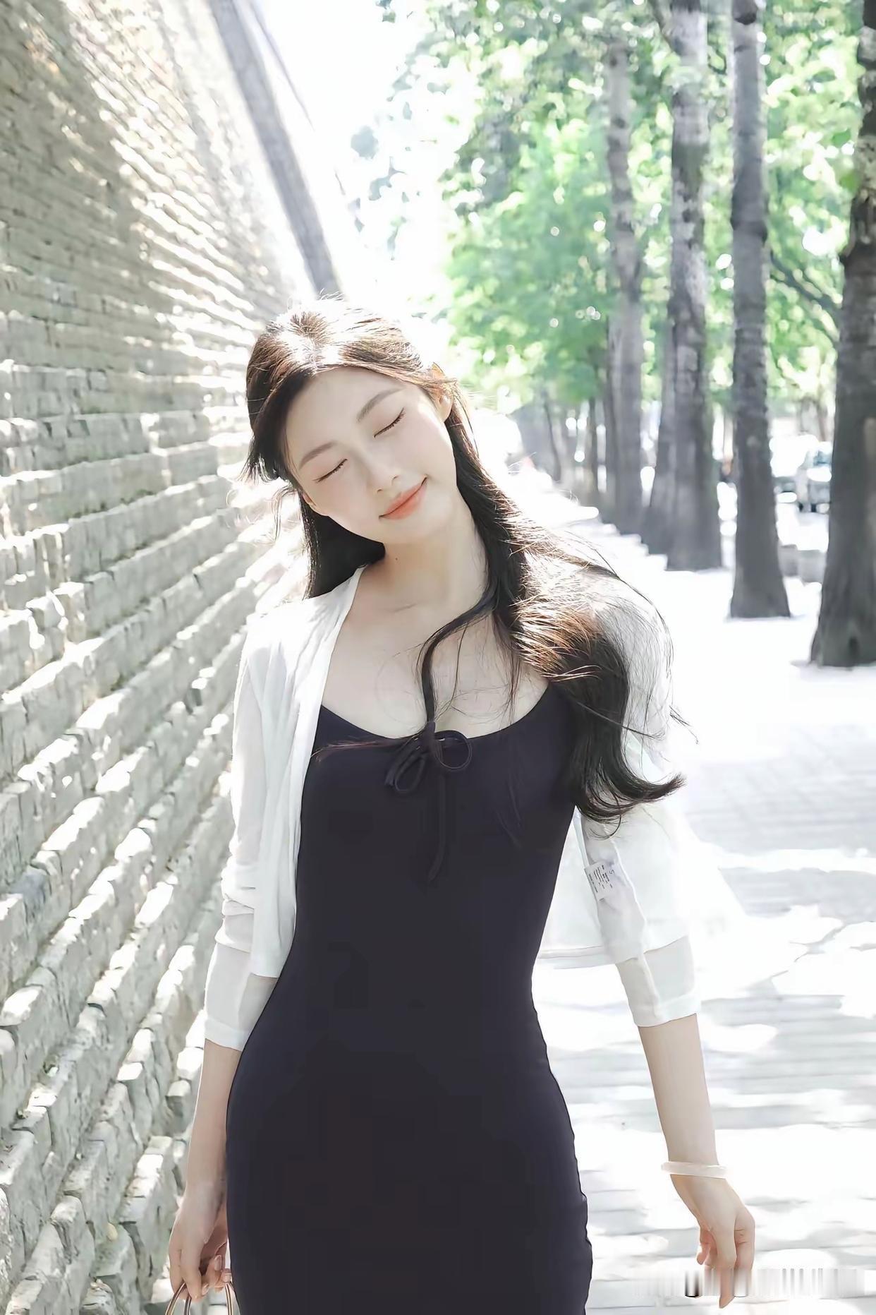 阳光下的优雅漫步，黑裙与白衬衫的完美搭配，尽显都市女性魅力。