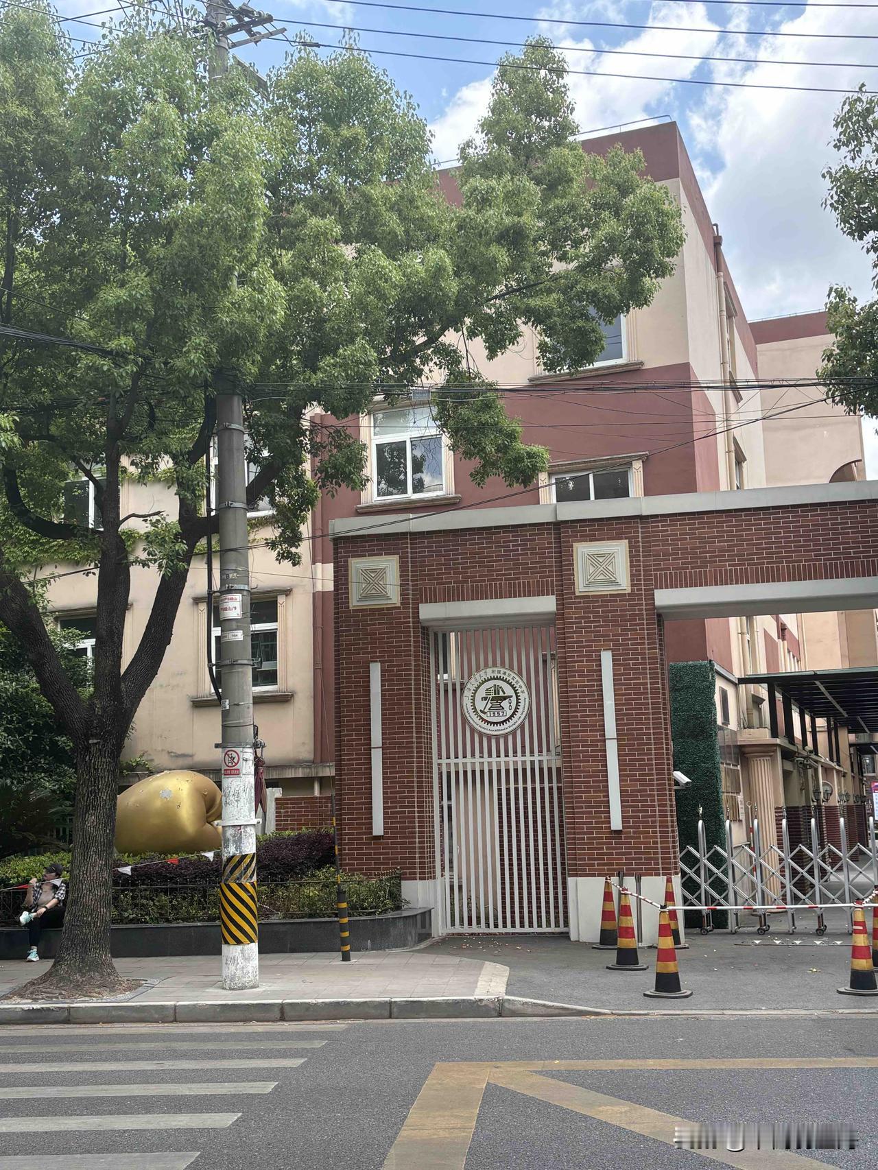 金苹果，是建平的吉祥物；
铁砧、铁锤、书是交大的特征。
哪个学校会在门口集上这两