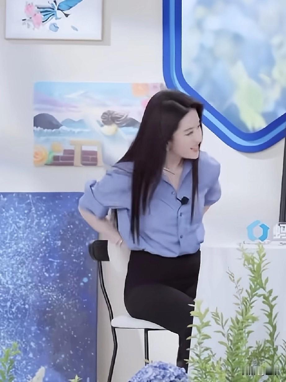 刘亦菲，她身着简约的蓝色衬衫搭配黑色下装，长发披肩