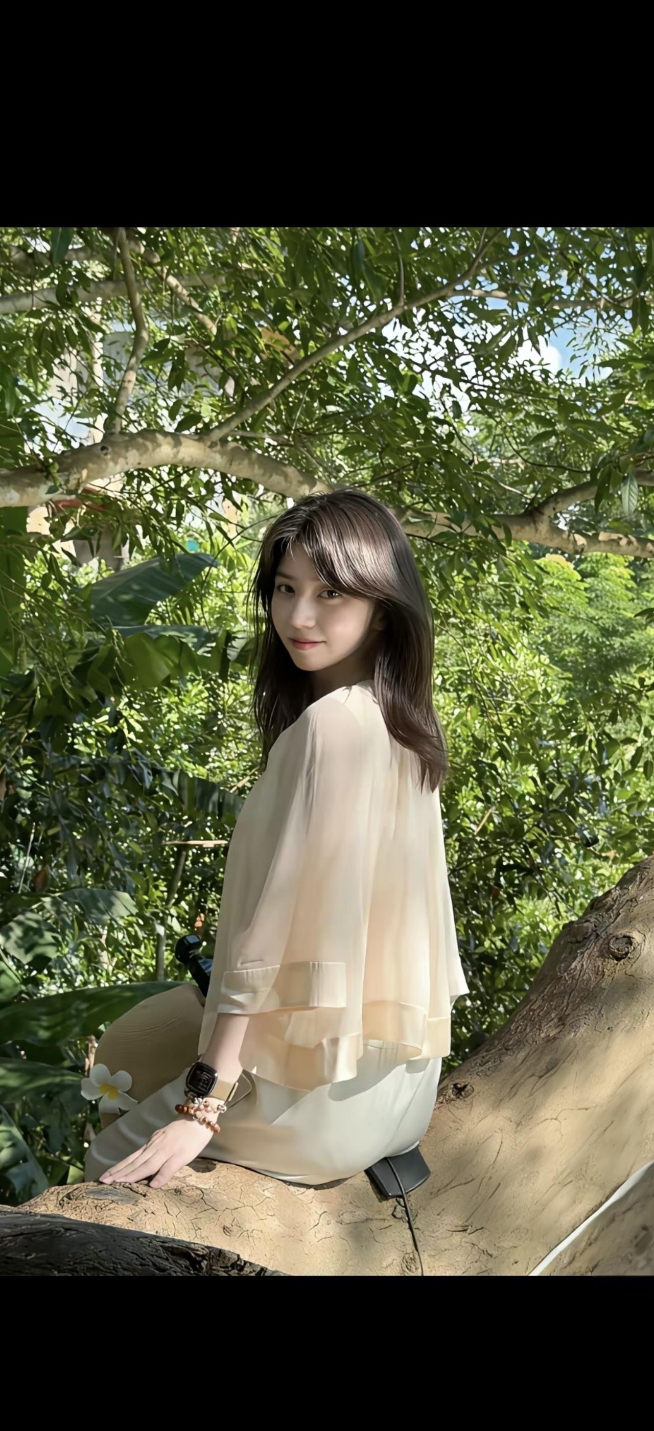 阳光明媚，女孩坐在树下，微笑着看向镜头。