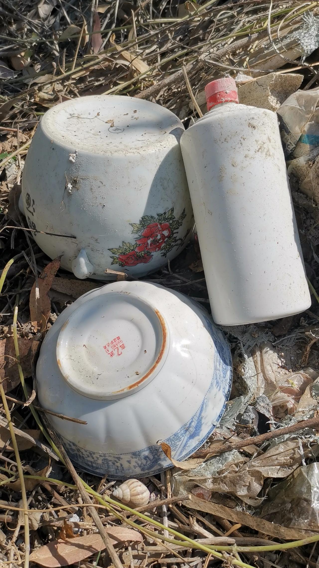 马路边的土堆上，静静地躺着一个白酒瓶、一个甜酒罐、一个白瓷碗，这要是当废品扔了又