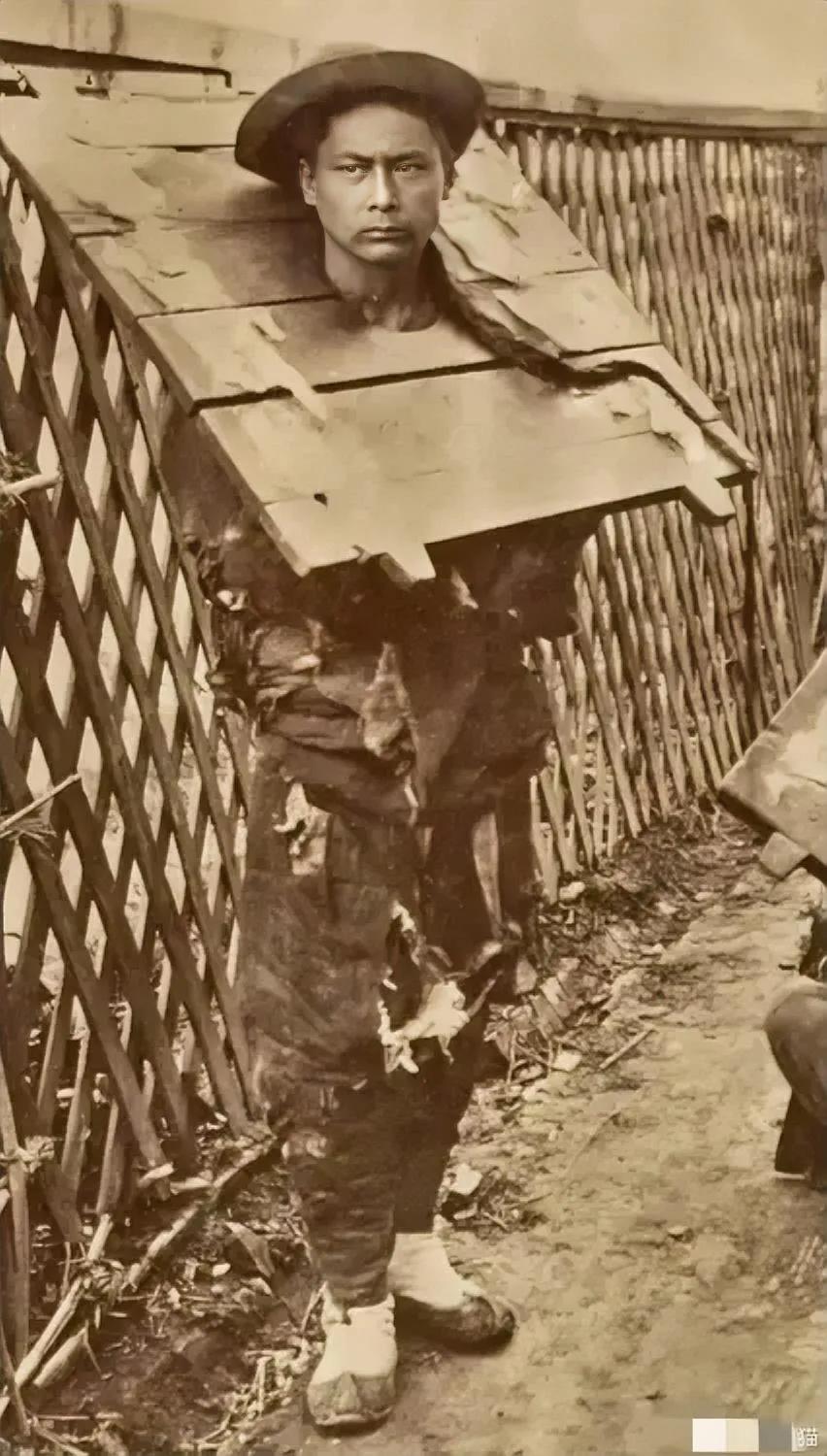 1890年，一名被枷锁禁锢的囚犯，照片中的他戴着一顶时髦的帽子，身上的衣服破烂不