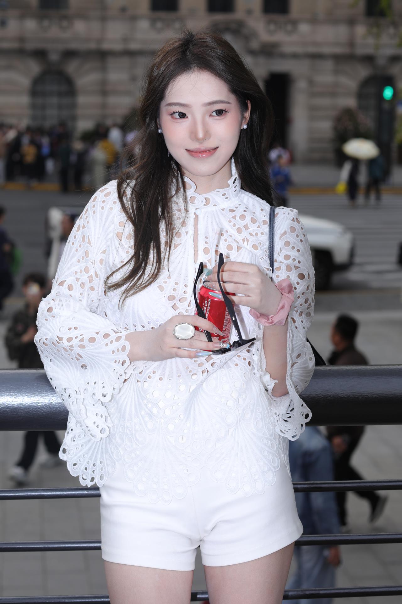 《白衫风语》
她身着一袭白色镂空蕾丝上衣，精致的花纹如花瓣般层叠，喇叭袖随着轻抬