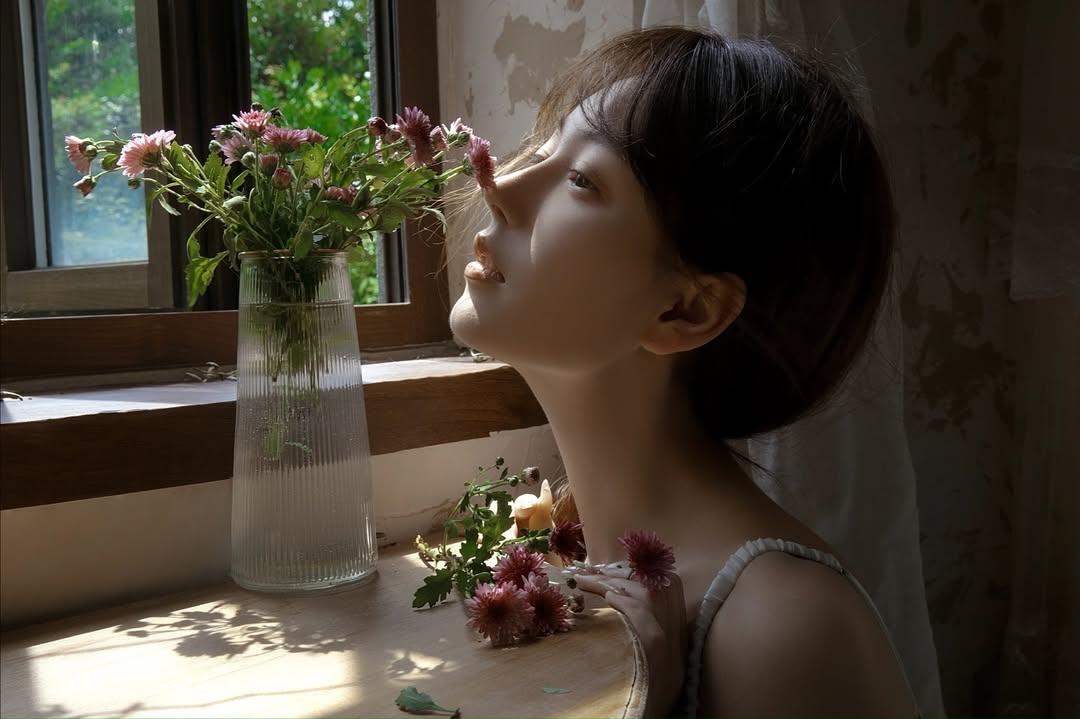 女孩在窗边闻着花香，享受阳光。
