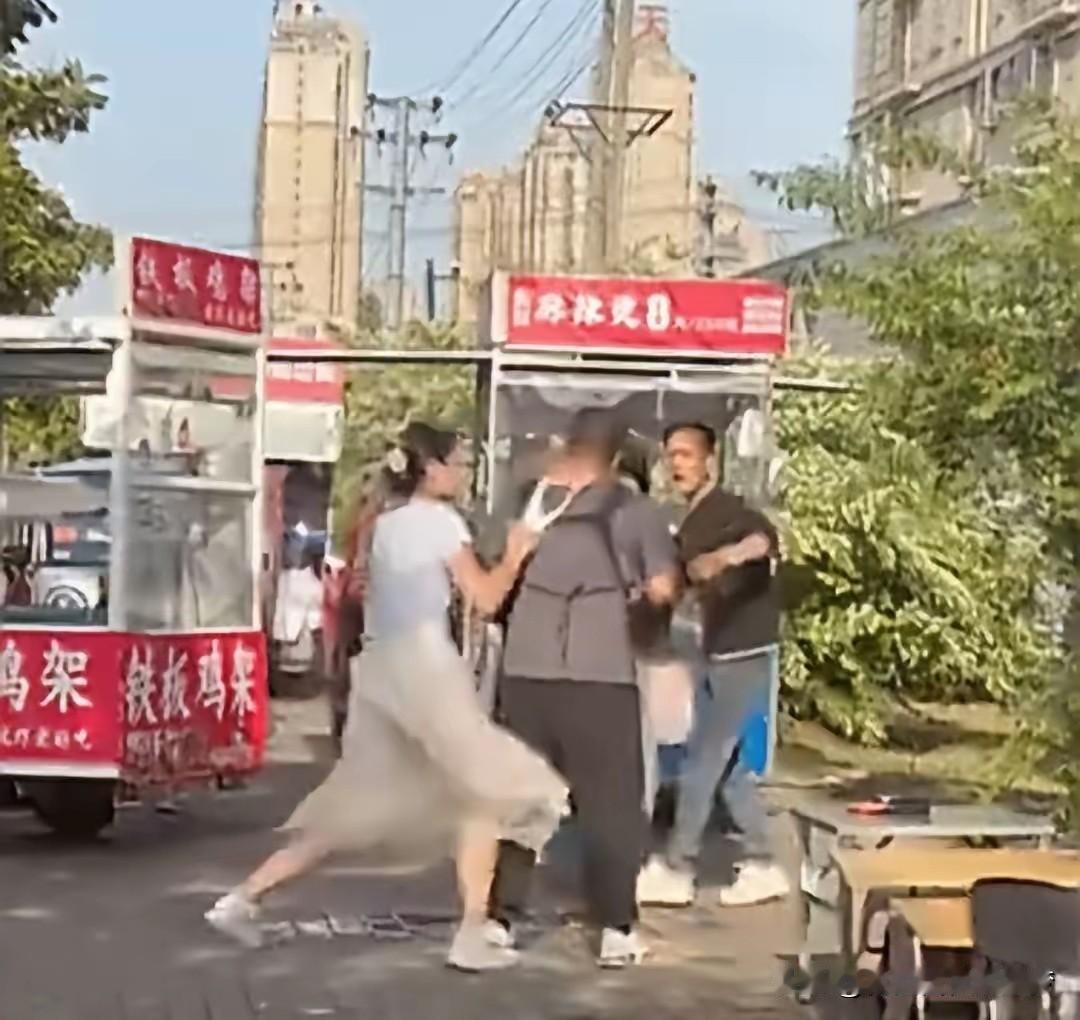 这个女人火了…
视频中，两个男的正在马路边人上吵架，大有愈演愈烈之势。
但是，另