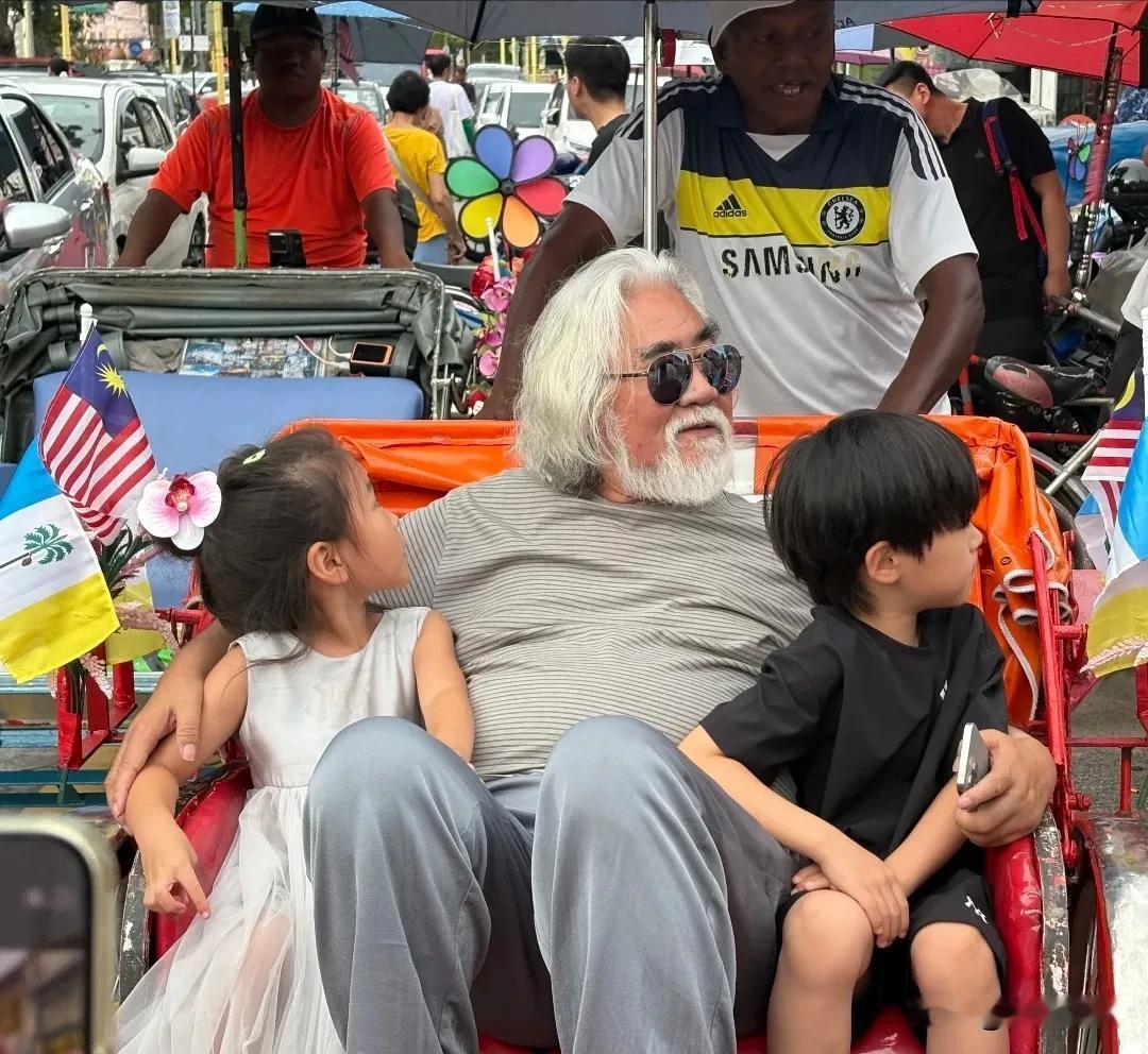张纪中带着老婆孩子去马来西亚槟城度假，体验当地的人力车。
74岁的张导须发皆白，