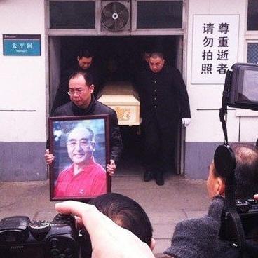 2013年正月，乒乓球运动员庄则栋葬礼，一张罕见的镜头，儿子抱着遗像缓缓走出太平