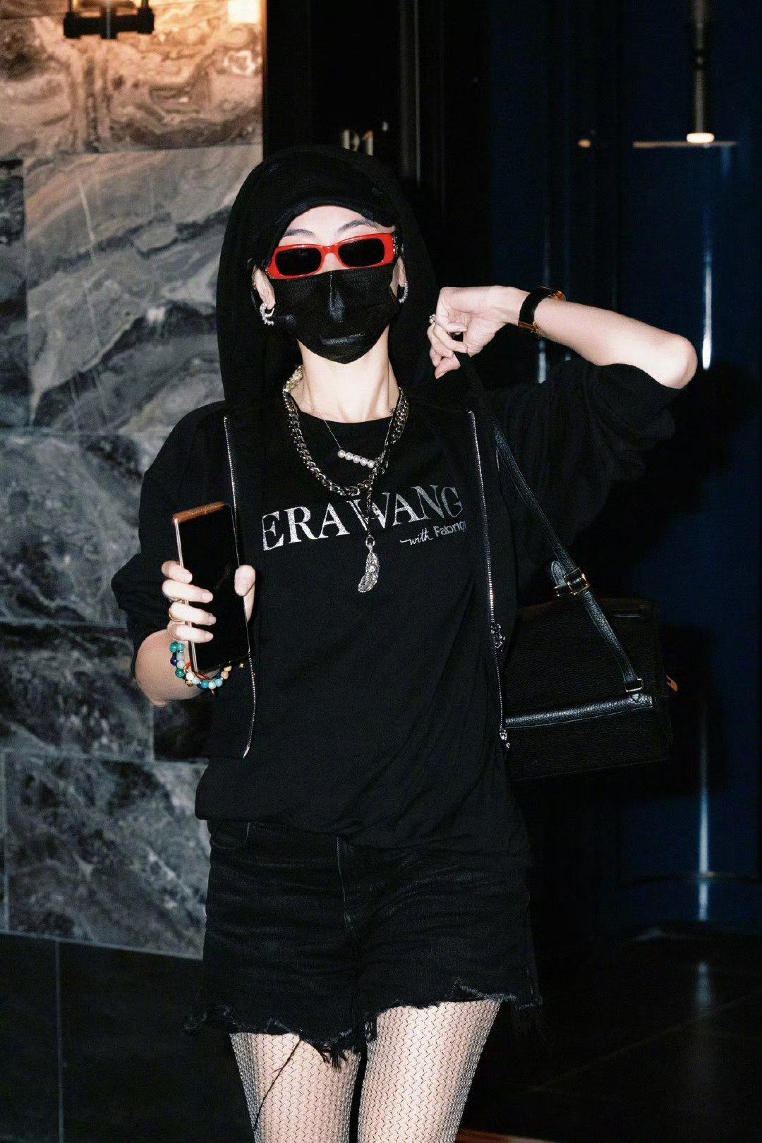 张柏芝这身黑色穿搭好酷呀！黑色短裤搭配黑色连帽衫，一身的黑色营造出朋克风来，又酷