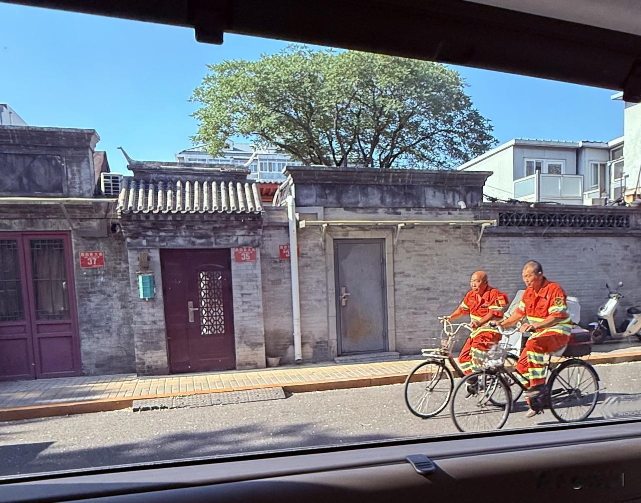 衣服鲜艳的环卫大哥，骑行在胡同里聊着天
胡同里的大树遮天蔽日，一看就凉快
这把摆