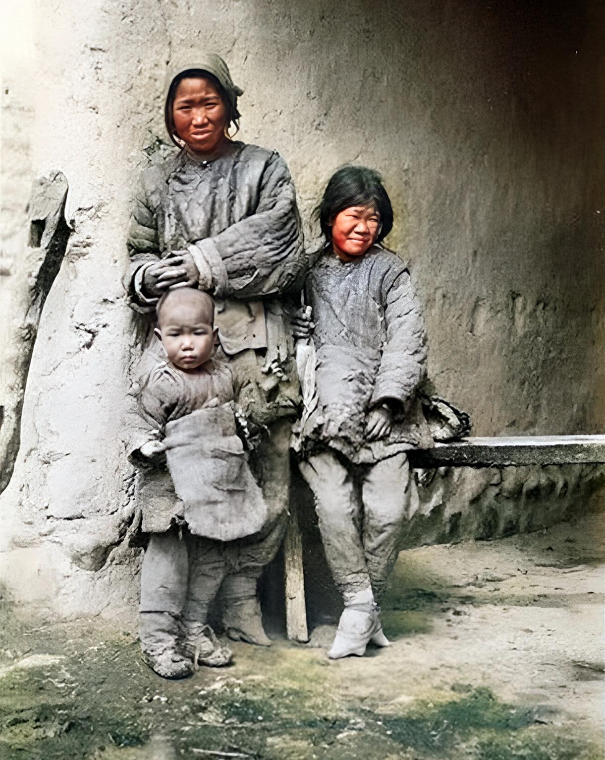 1906年，晚清，河南，一个女人带着两个孩子，在自家窑洞前晒太阳。

食不果腹，