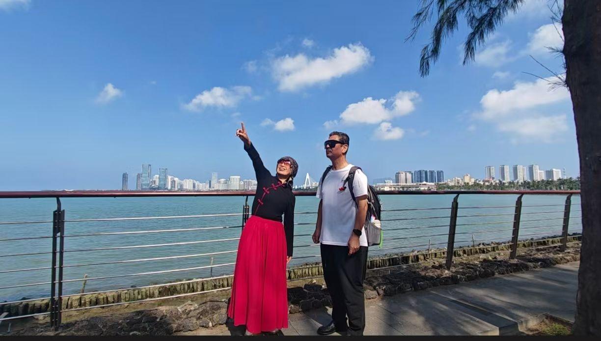 🌊 海风吹着蓝丝绒般的天，她指向云的刹那，城市与浪都成了背景。
✨ 红裙在海边