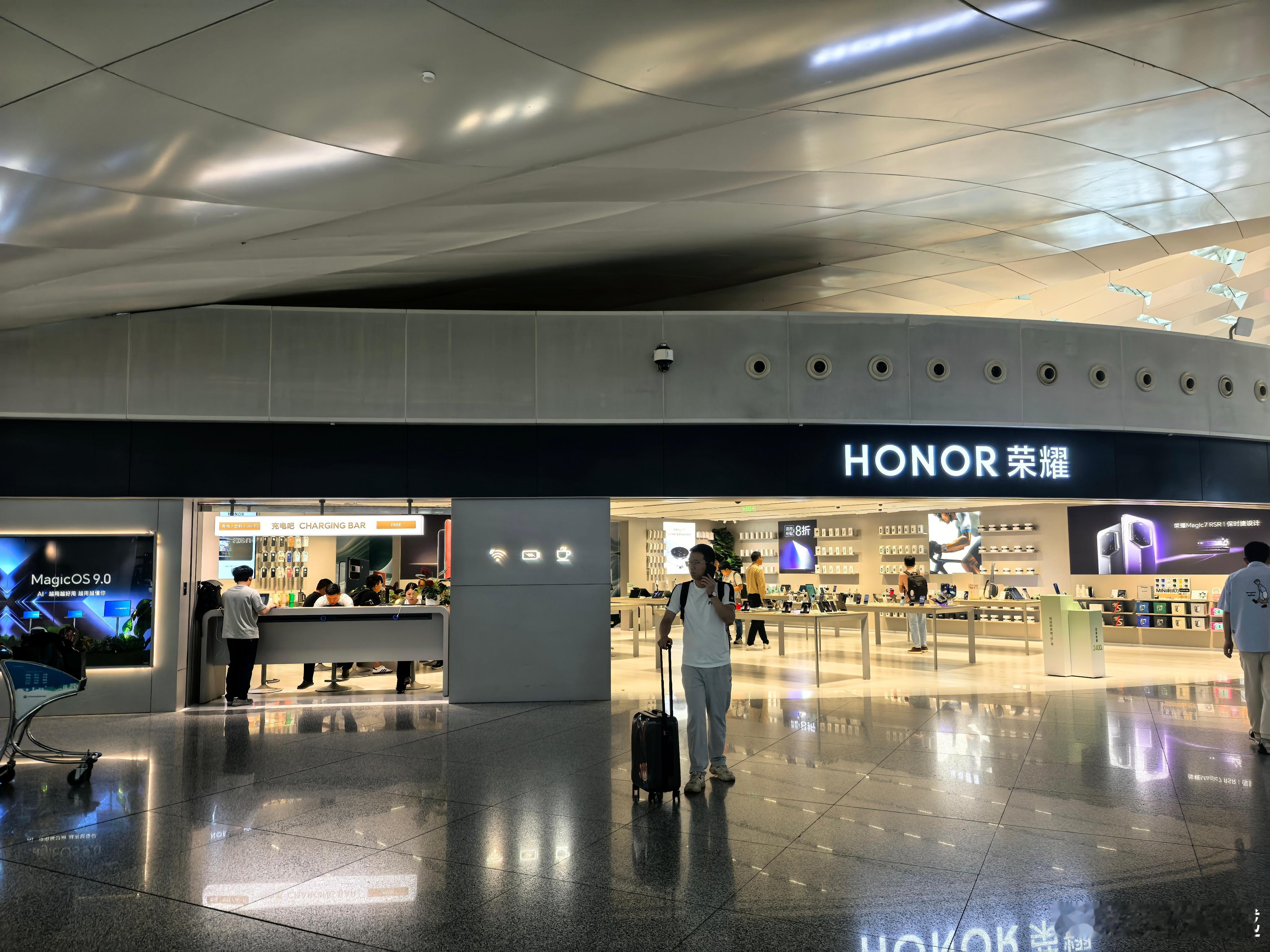 路过深圳机场，随手拍下荣耀门店，门店左边有个充电区域，补电、联网、喝水都可以，最