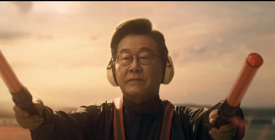 韩国总统李在明在APEC宣传片里演地勤指挥，这事儿挺有意思。他拿着荧光棒指挥飞机
