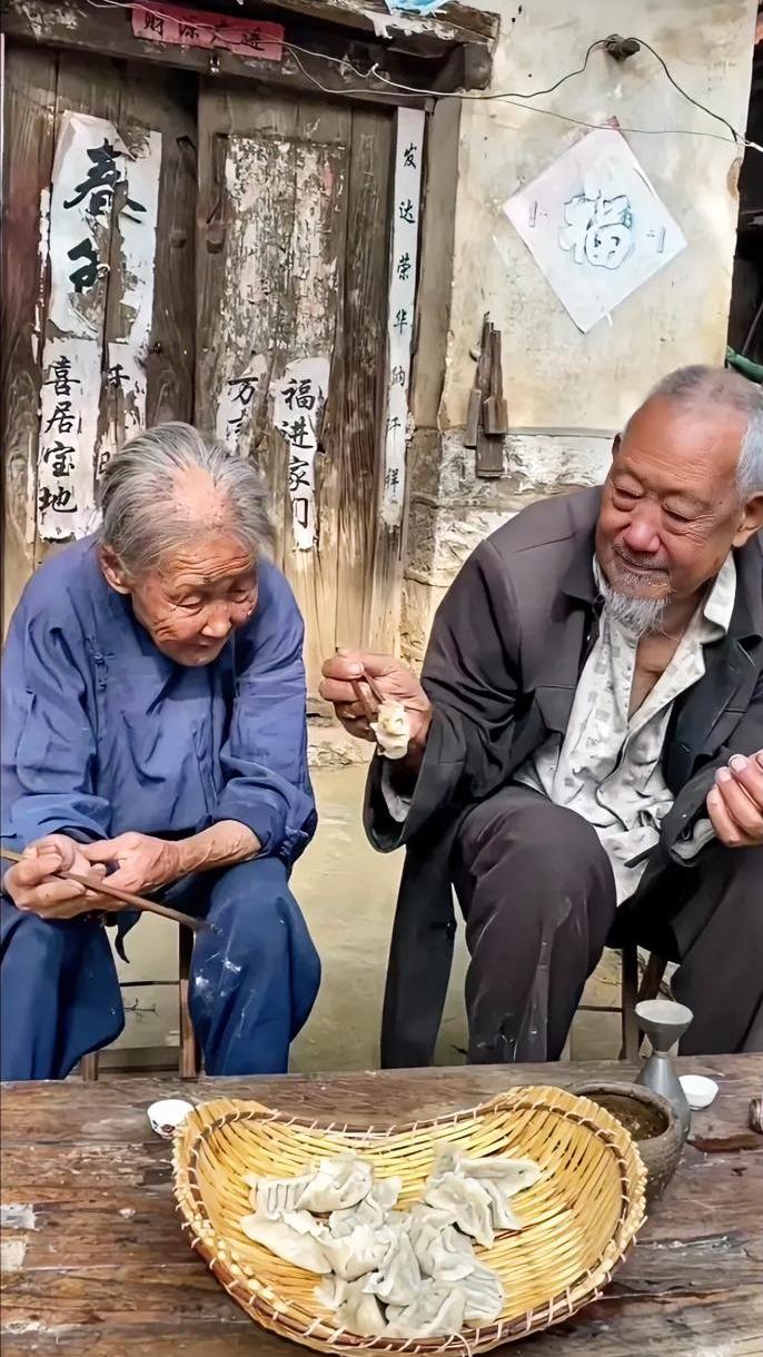 老旧木门贴着褪色春联，院里竹簸箕盛满手工水饺，两位老人相伴而坐。奶奶低头细细捏着
