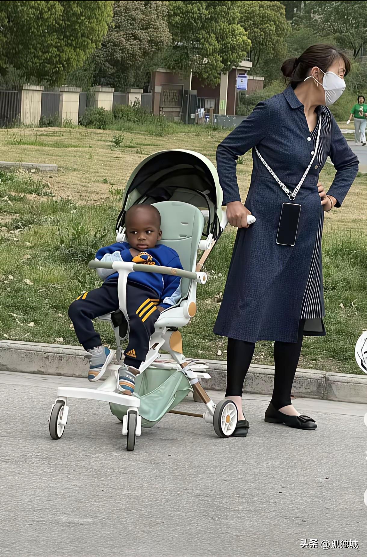 不知道这是奶奶带孙子还是外婆带孙子，遛孩子戴口罩的还真是少见，这黑孩子万一丢了不