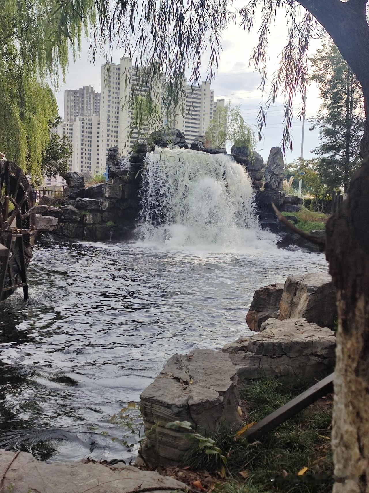 公园一角有感：

公园一角现瀑布

风景如画止住步

四周垂柳随风拂

拍张照片