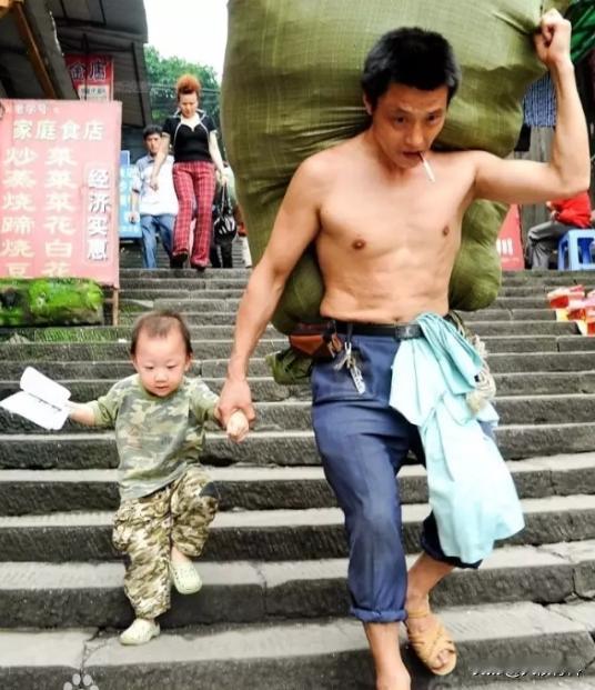 2000年，一张父子照火遍全国，一个瘦弱的中年男人，扛着满满一袋货物，嘴里叼着一