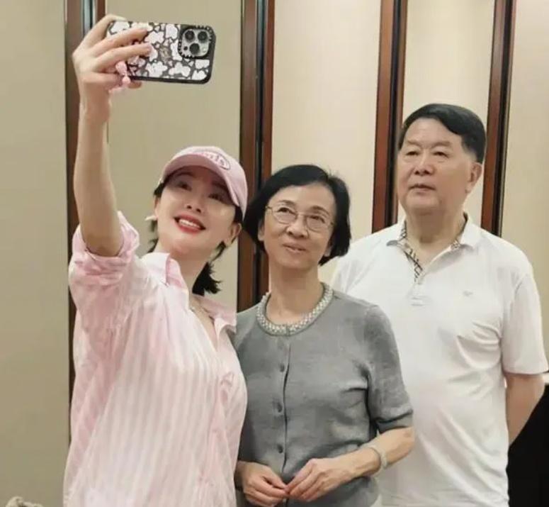 年近五旬的左小青回老家看望爸妈，一家三口合影好温馨！她穿粉色衬衫配棒球帽，温婉娴