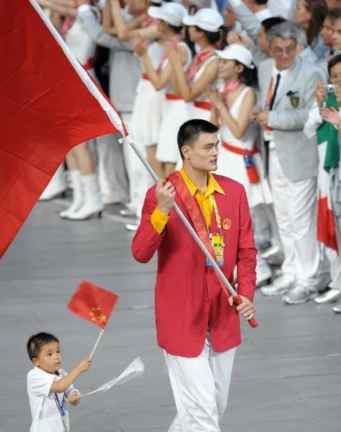 2008年奥运会开幕式上，姚明高举红旗走在人群正前方。

导播室里，张艺谋盯着监