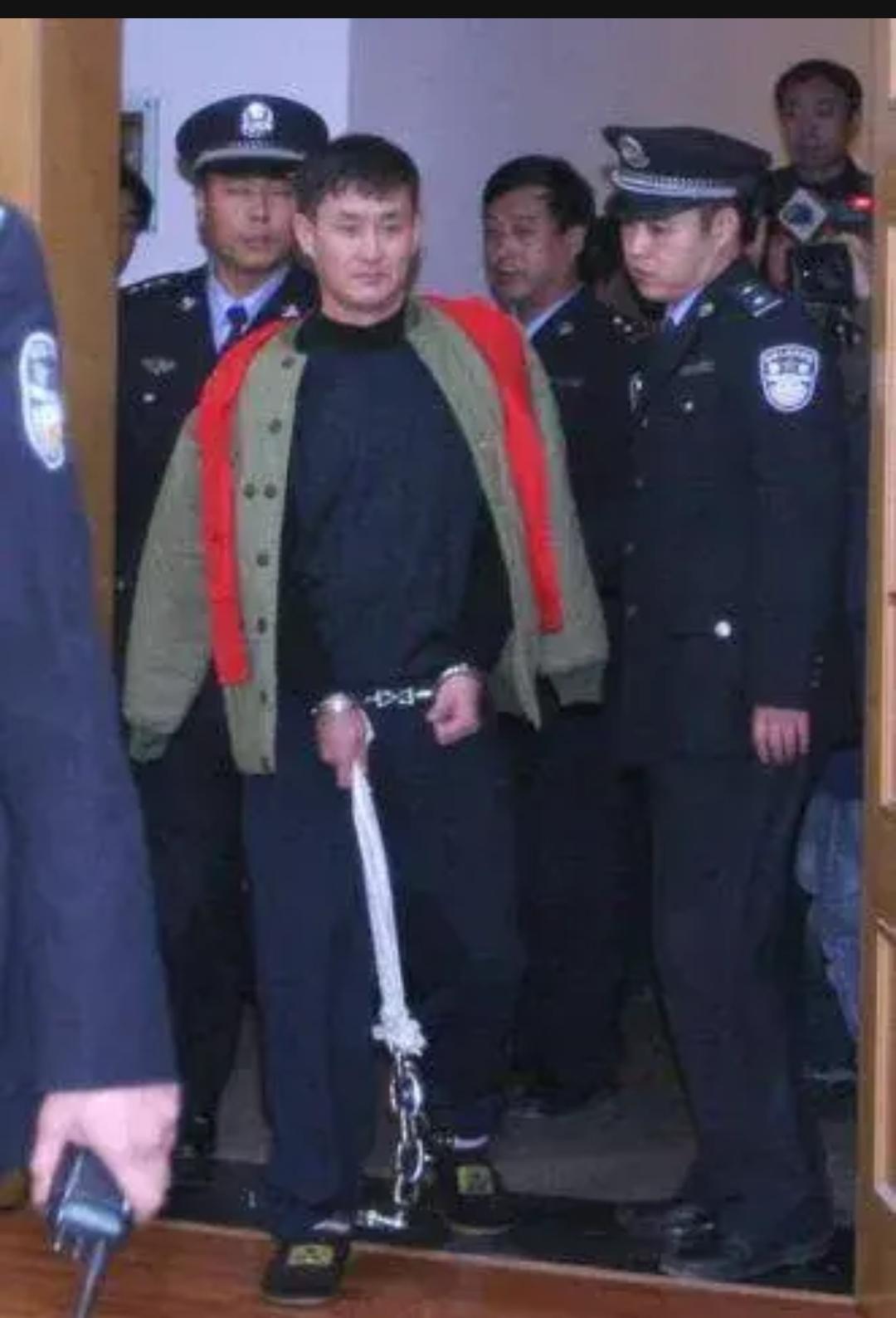 2006年11月9日，沈阳"1·18"大案开庭审理，主犯张显光戴着手铐，提着沉重