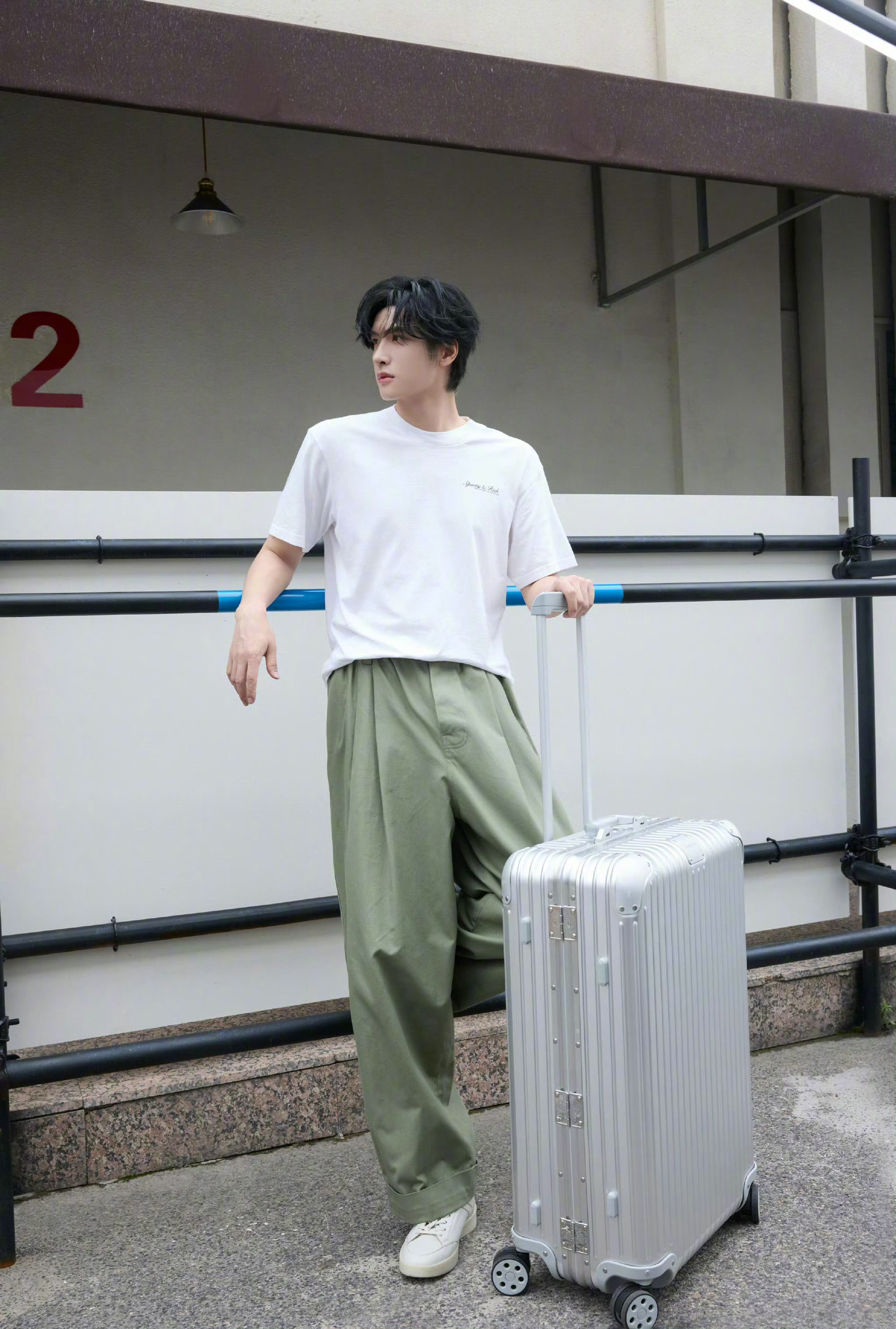 展轩出镜RIMOWA行李箱宣传造型。Sporty & Rich T恤与棕绿色裤装