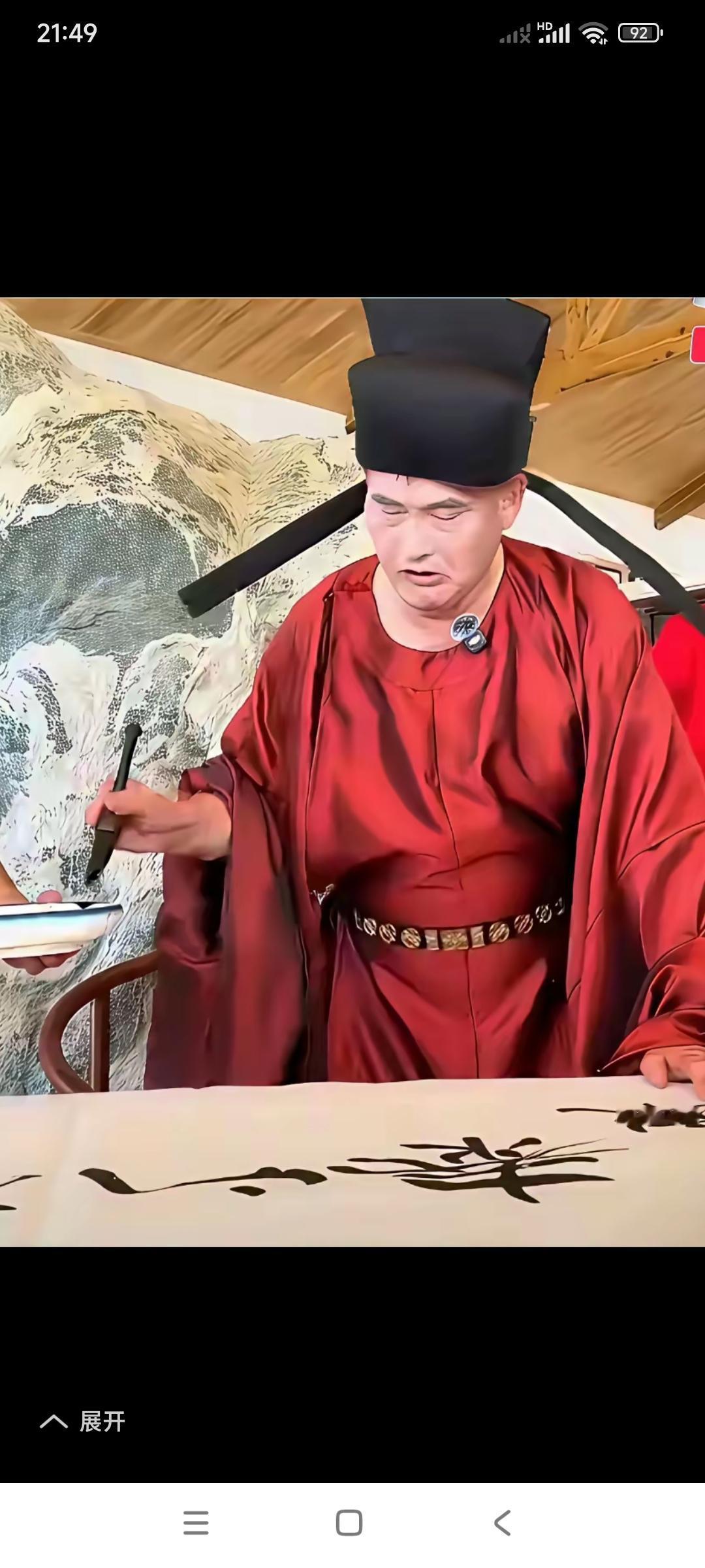 这才是大书法家的模样。

头冠乌纱帽，身穿县官服。

有人端着砚台，朱之文有模有