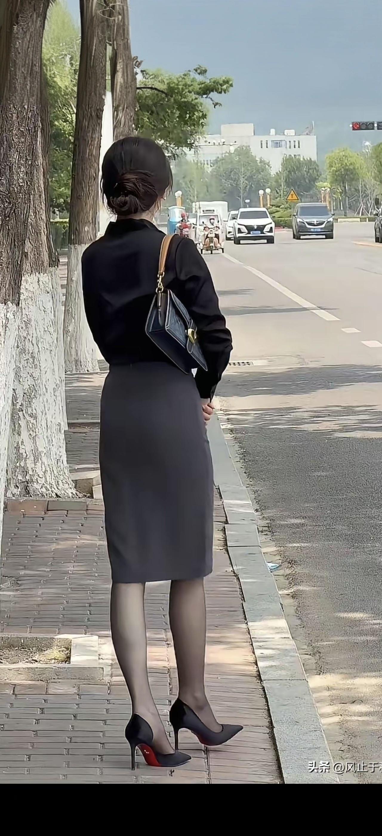 一个穿黑裙子的女士在等车。