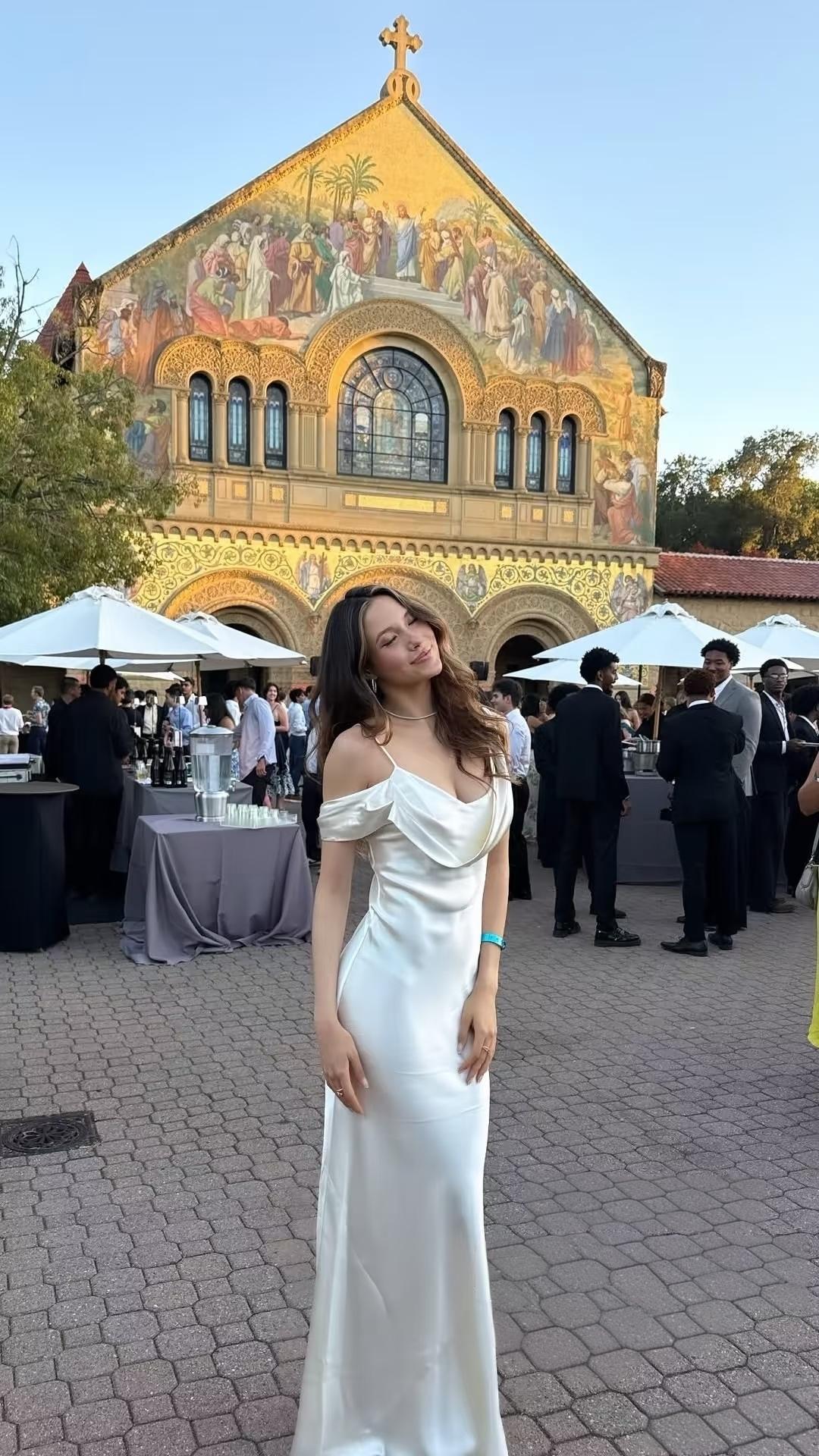 谷爱凌穿着一袭象牙白缎面长裙参加斯坦福毕业典礼，
流畅裙身顺着肩线落下，
贴合着