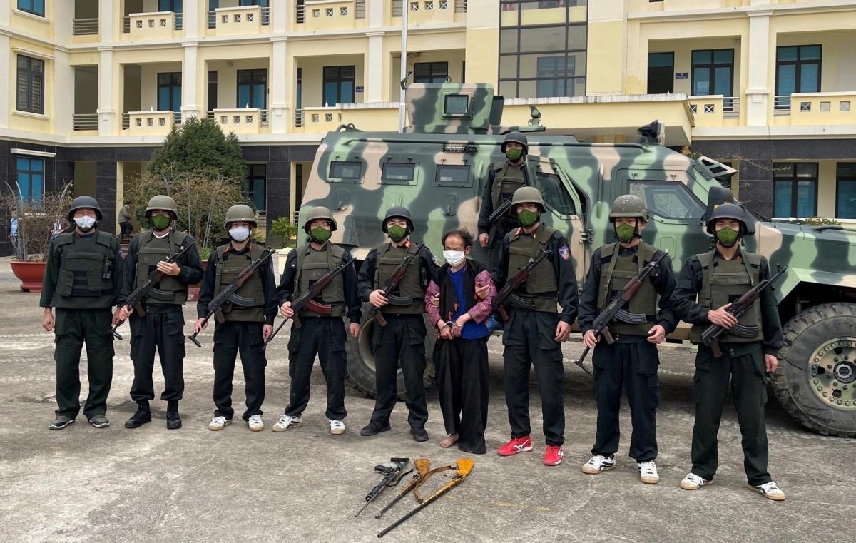 越南机动警察与抓获的毒贩合影，地上三支枪，后边是阿联酋生产的装甲车
