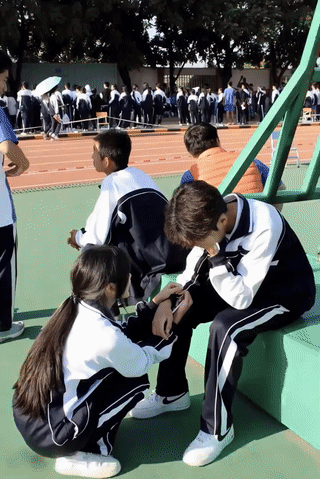 男孩在校园运动会上因为没有发挥好，导致他心情有点低落？
一名女孩蹲在他旁边正在安