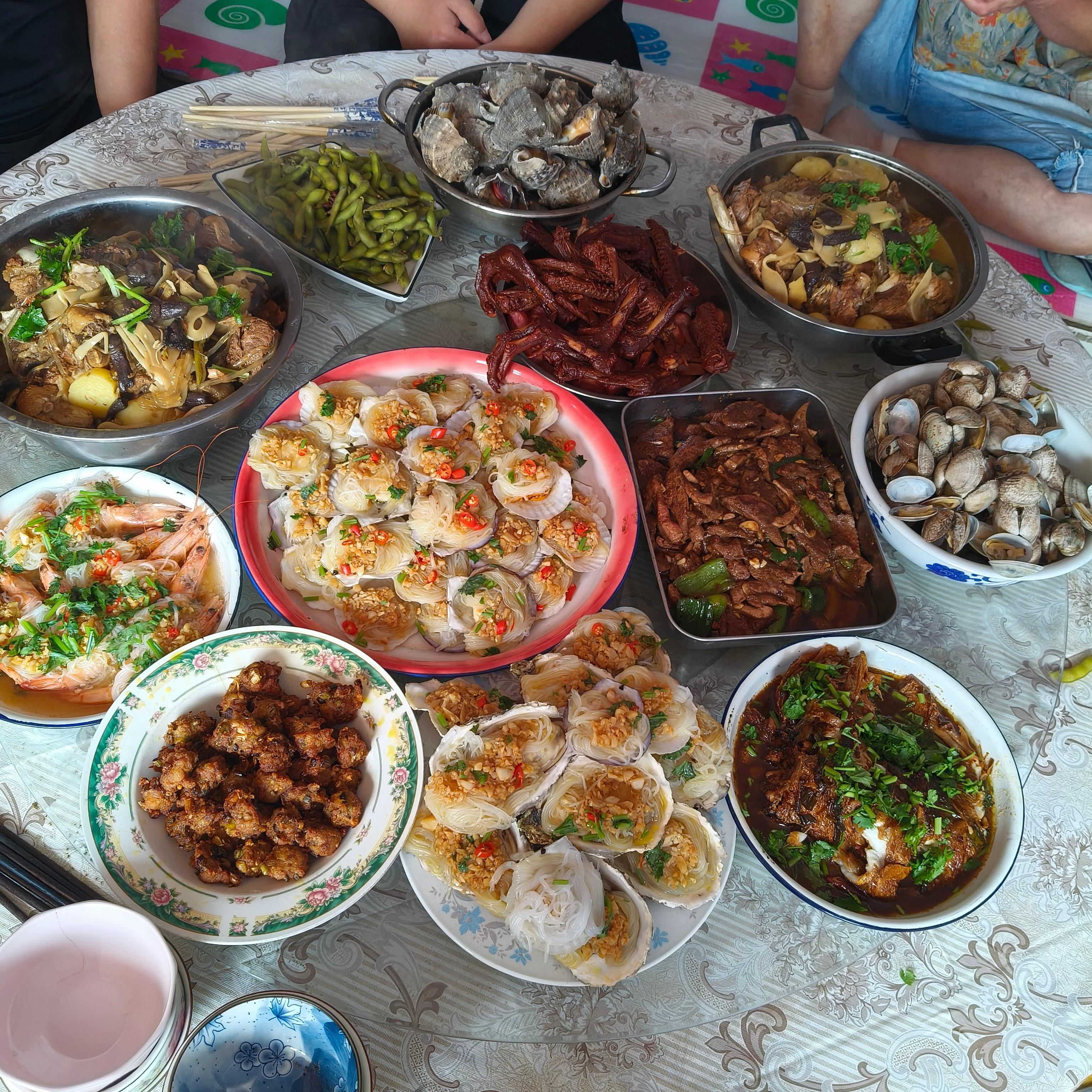 圆桌铺开人间烟火，八碟十碗盛满笑意与乡音。青瓷白釉映着油光，蒸腾的热气里藏着最朴