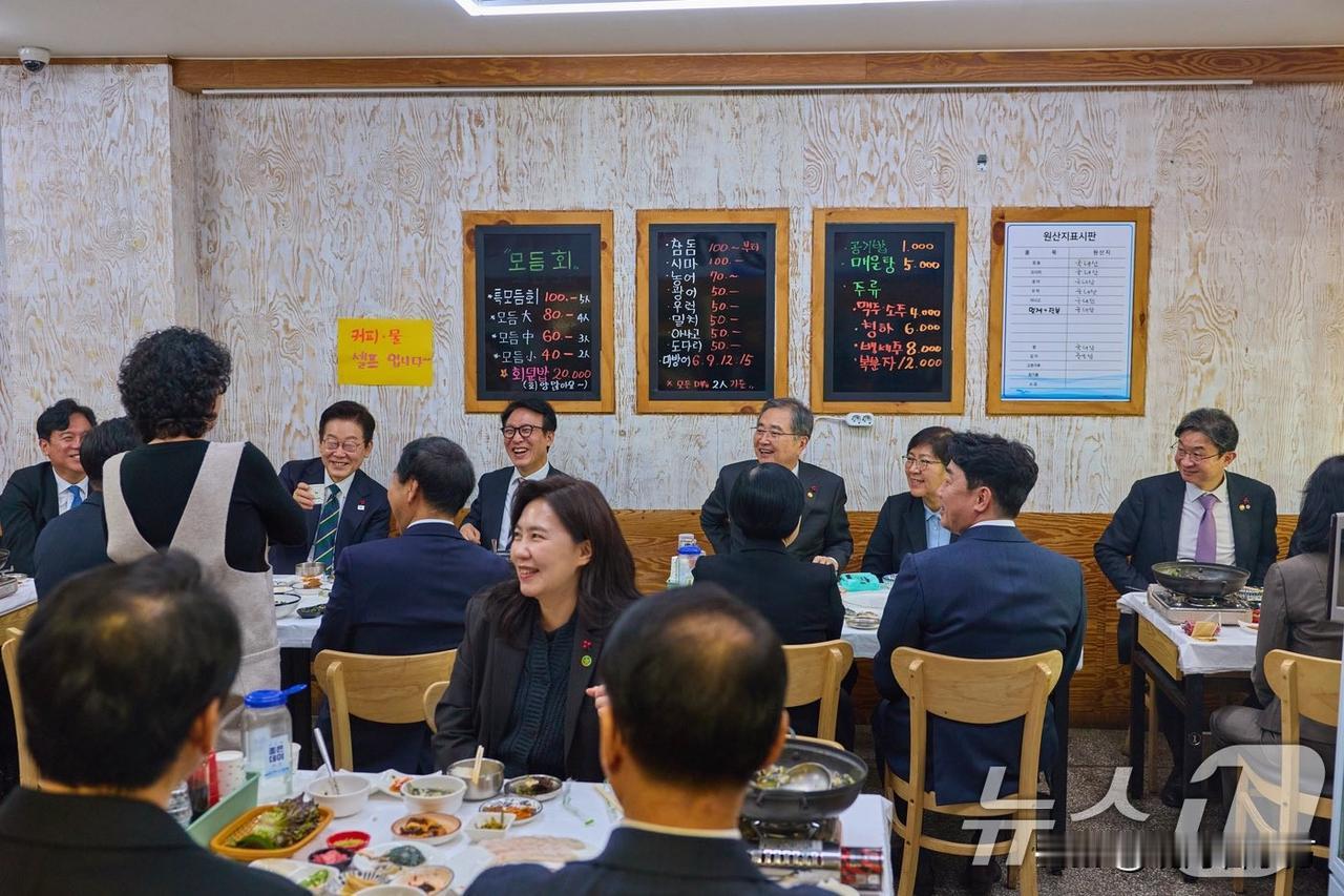 今天李在明在釜山结束国政会议后，去当地饭馆聚餐。我们可以从照片背景的墙上看到这个