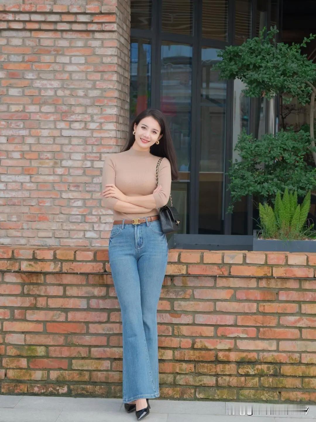 都市街头，那个在砖墙前微笑的时尚女孩，简直是一道亮丽风景。她身着牛仔裤搭配高跟鞋