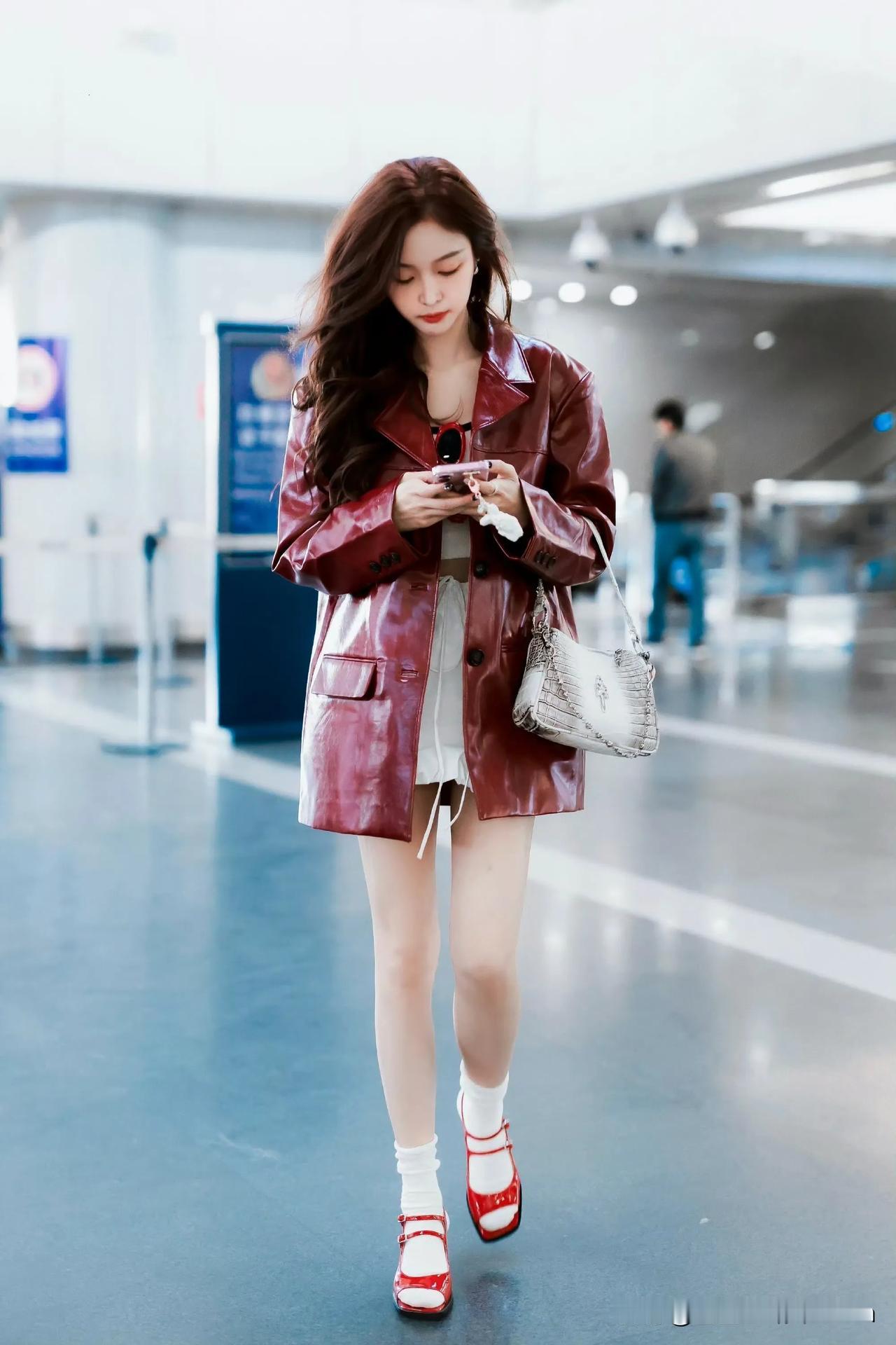 吴宣仪红衣佳人立机场，手机轻按笑盈盈