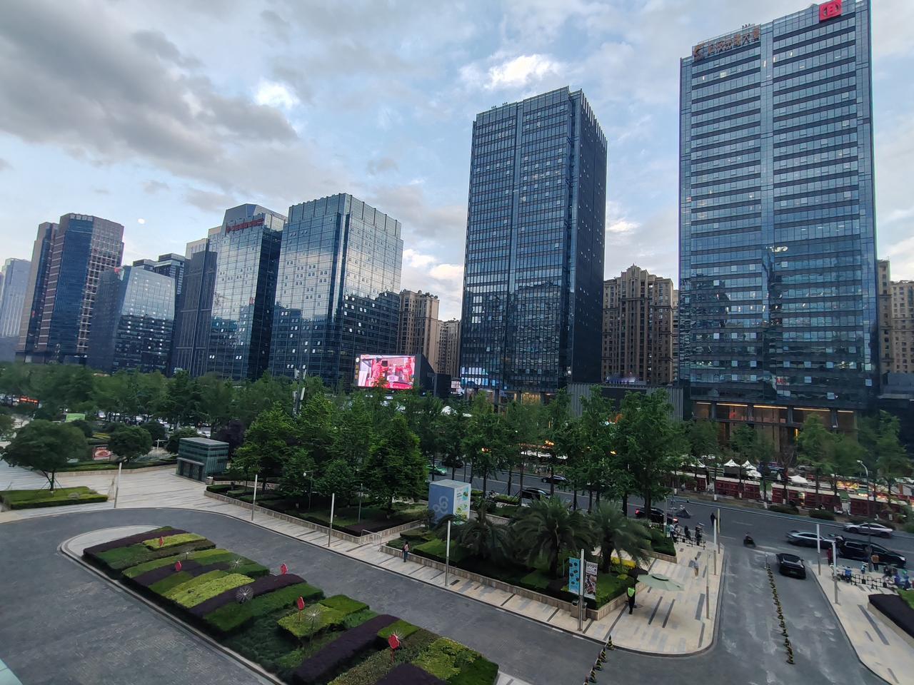 傍晚时分，仰望这片城市天际。摩天高楼错落矗立，满目青翠点缀街巷，繁华都市与自然绿