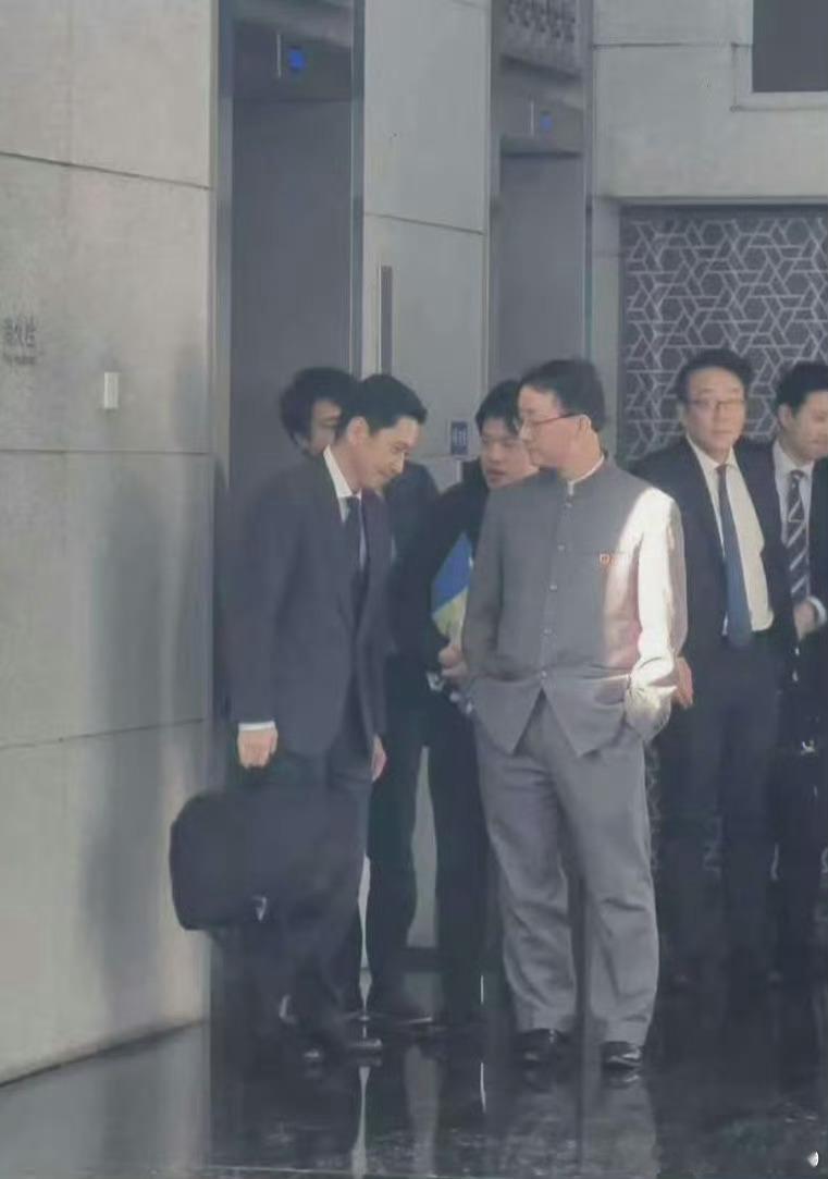 照片里中国外交官特意穿的立领中山装酷似日本中学生制服。双手插兜，俯视点头哈腰的日