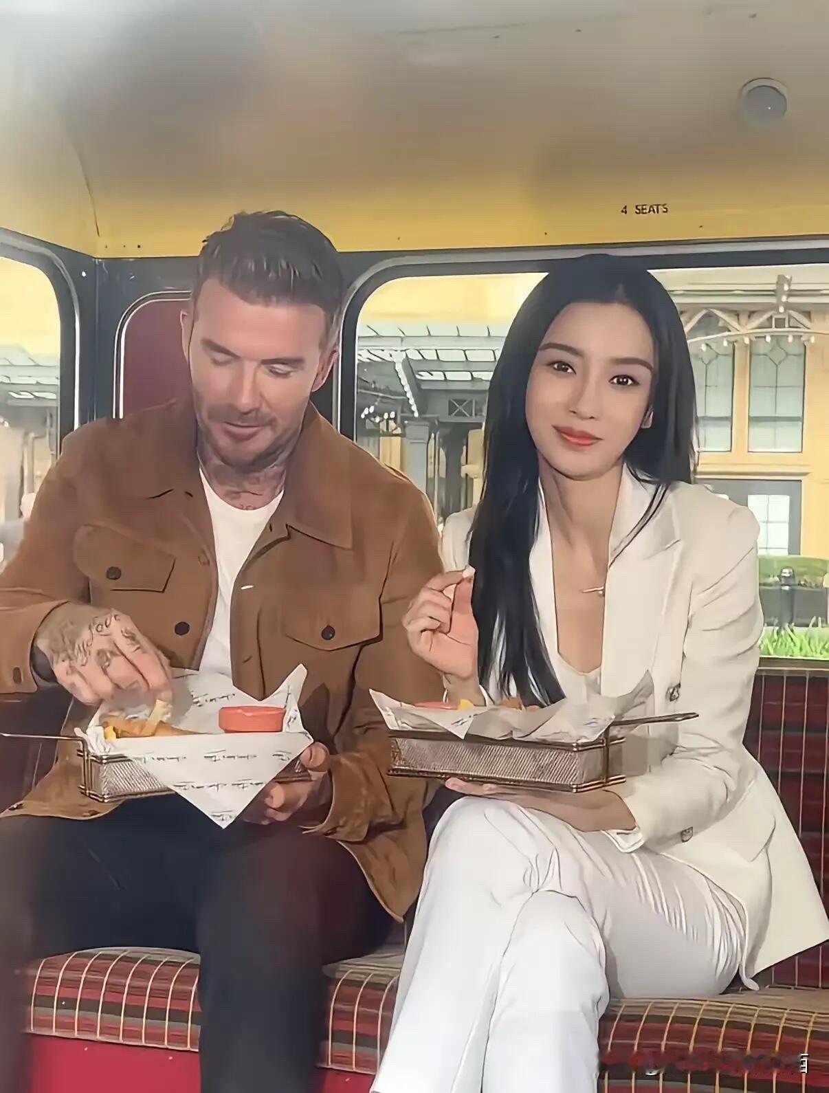 估计照片中的美女心里已经乐开花了，毕竟能跟巨星贝克汉姆坐在一起吃东西，应该是很多