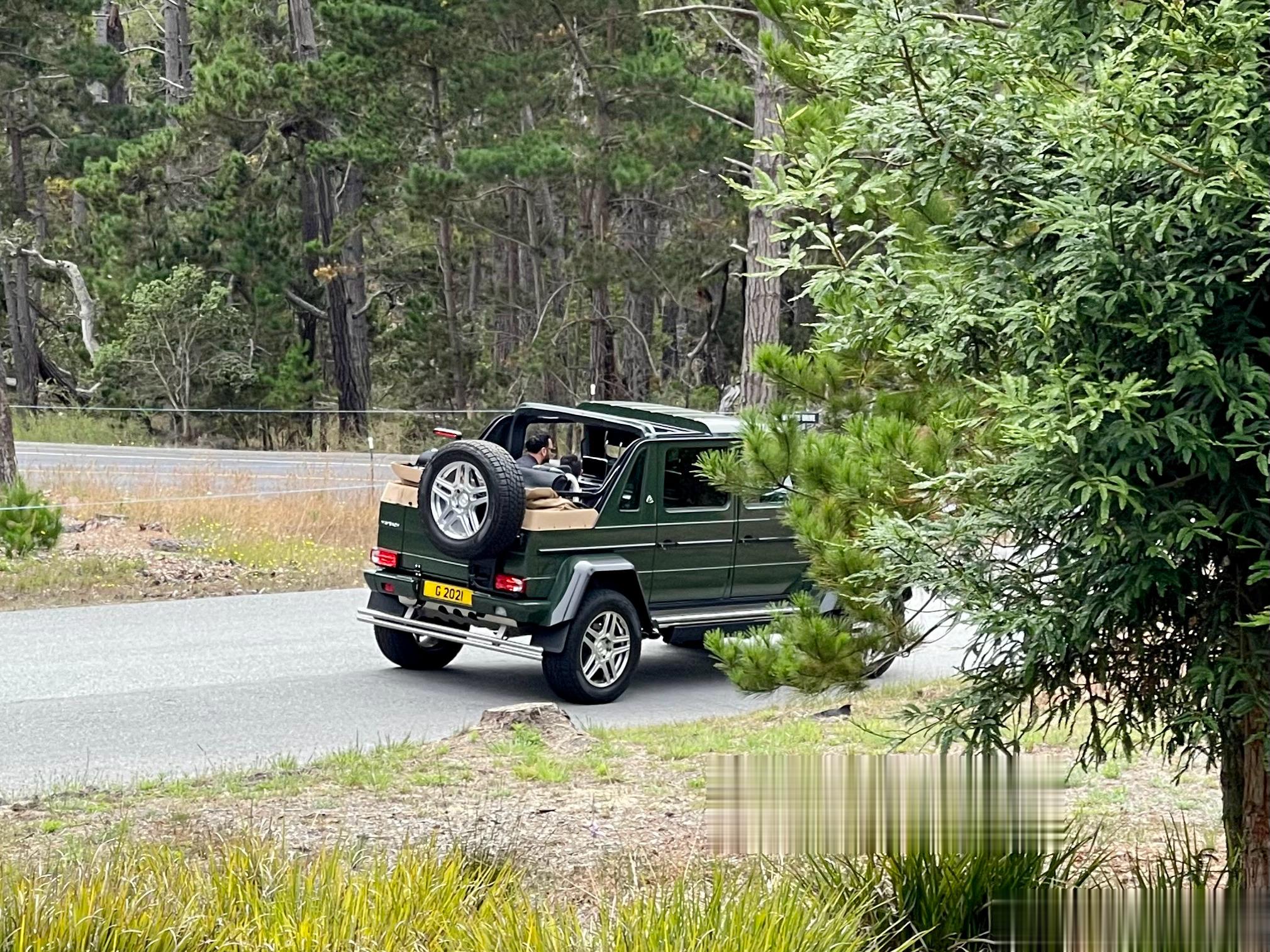 一对父子，坐在敞篷车中，感受圆石滩的氛围，与众不同的是，这辆敞篷车是辆大G，还是