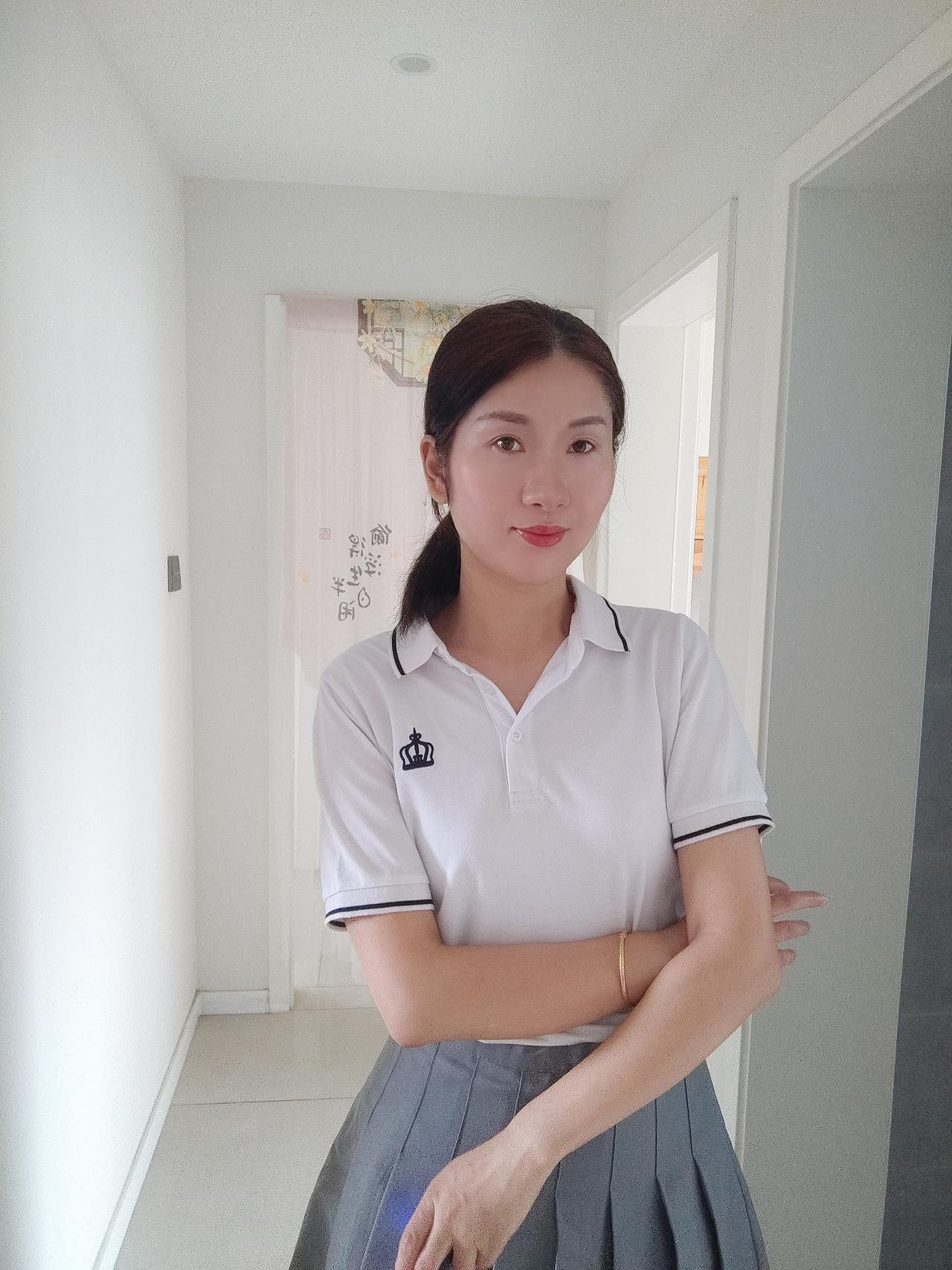这女生穿着校服，微笑着拍照。