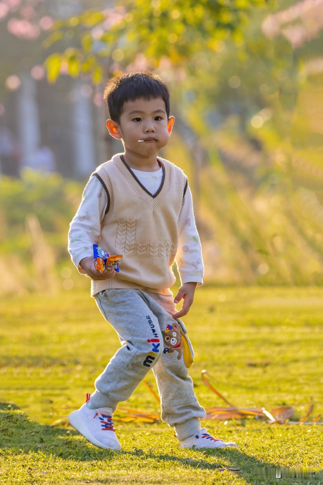 夕阳余晖照小童，蹦蹦跳跳心欢畅。
嘴中糖果甜如蜜，手里零食乐无穷。
幸福时光无限