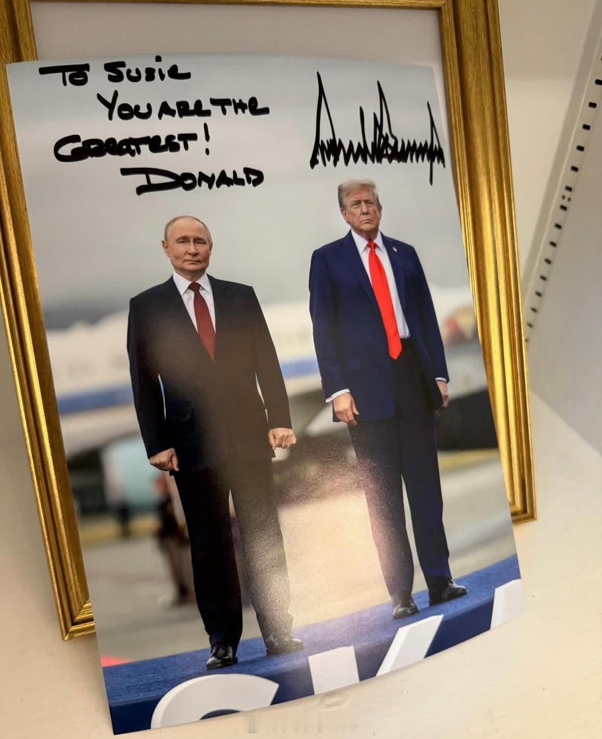 特朗普送给最信任的、白宫幕僚长苏西威尔斯的签名照，是他和普京在阿拉斯加的合照 