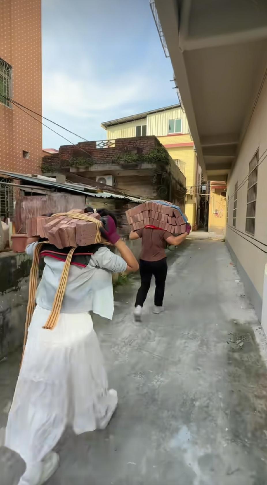 搬运工大姐扛着沉重的红砖头，不时回头看看身后跟着扛砖的女孩，眼里瞬间就涌出了泪花