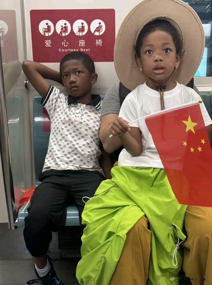 地铁上看到两个黑人小孩坐在椅子上，其中有一个小孩手上还拿着中国国旗？
刚开始还以