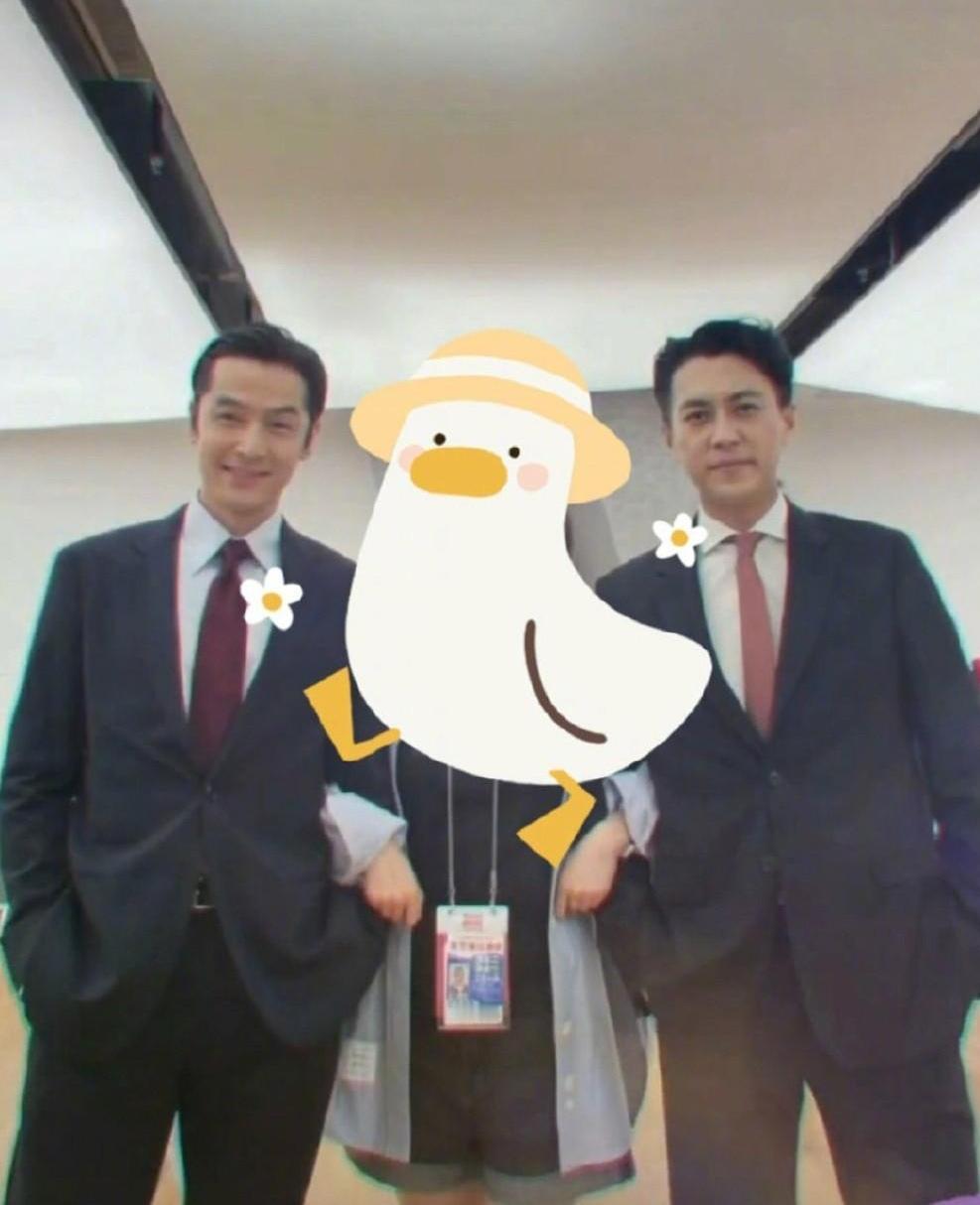 两位西装革履的大帅哥同框：胡歌发型一丝不苟，容颜明亮俊秀，左侧眉毛高挑，看上去真